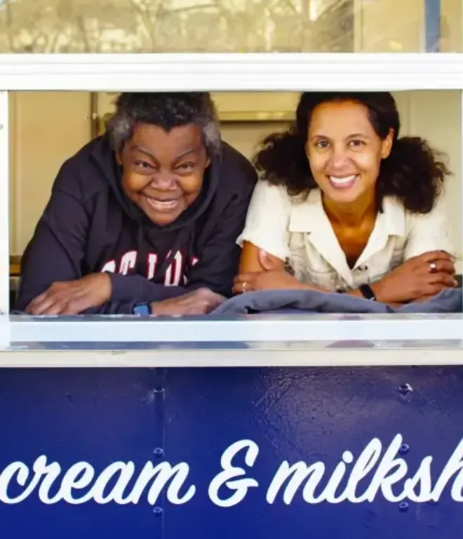 The MilkMade owners smiling from the window of their ice cream trailer